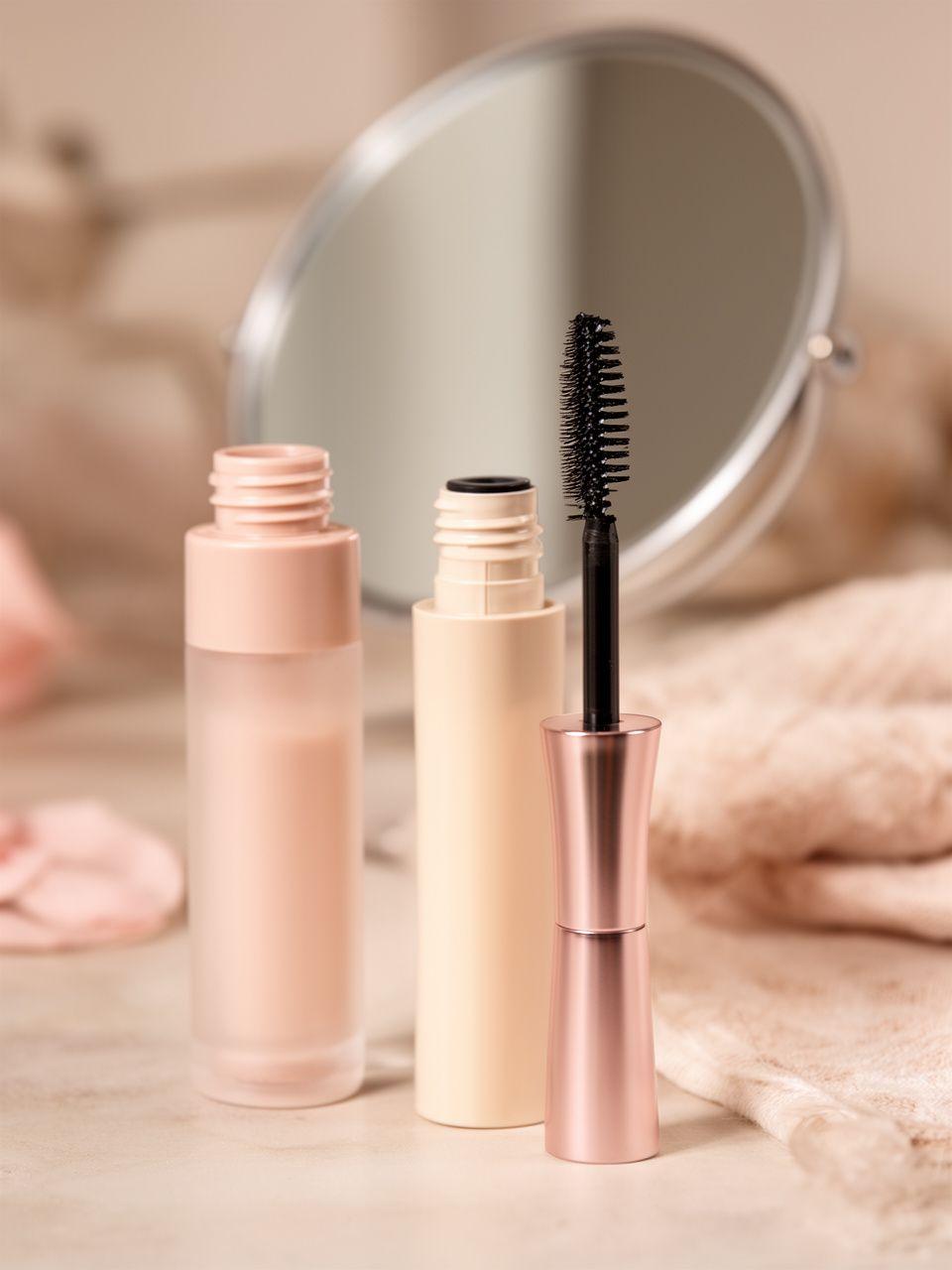 Wimpernserum und Pflegebürste neben einem Spiegel in einem ruhigen Beauty-Studio mit natürlichen Beigetönen